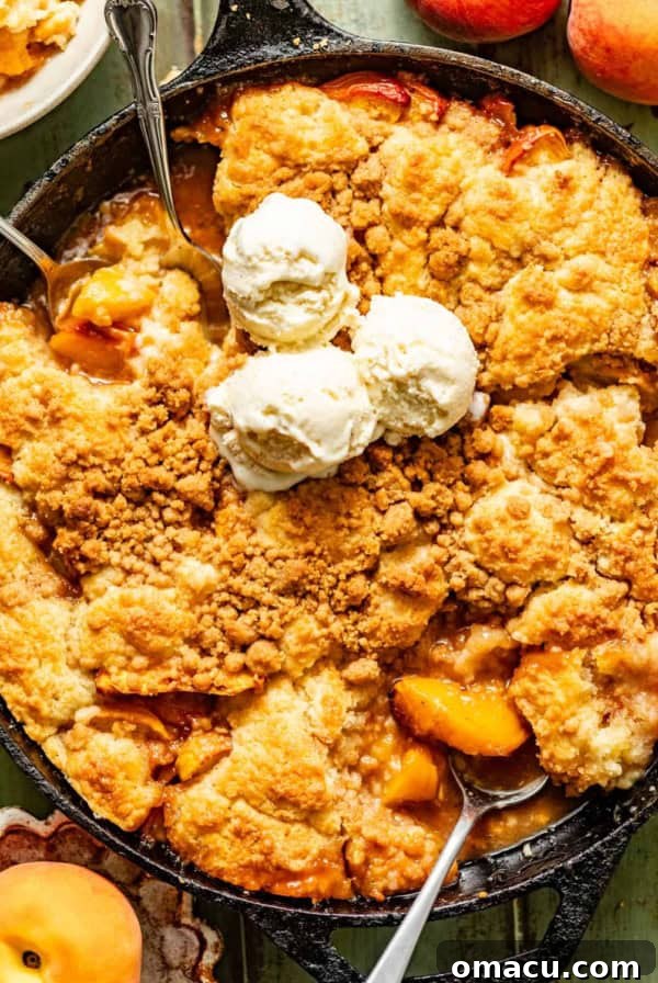 Skillet Peach Fritter Cake with Vanilla Bean Glaze 11 peach cobbler in a cast iron skillet topped with ice cream and fresh peaches on the side.
