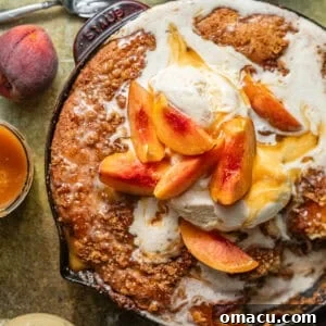 Skillet Peach Fritter Cake with Vanilla Bean Glaze 12 peach fritter cake in a skillet topped with ice cream and fresh peaches.