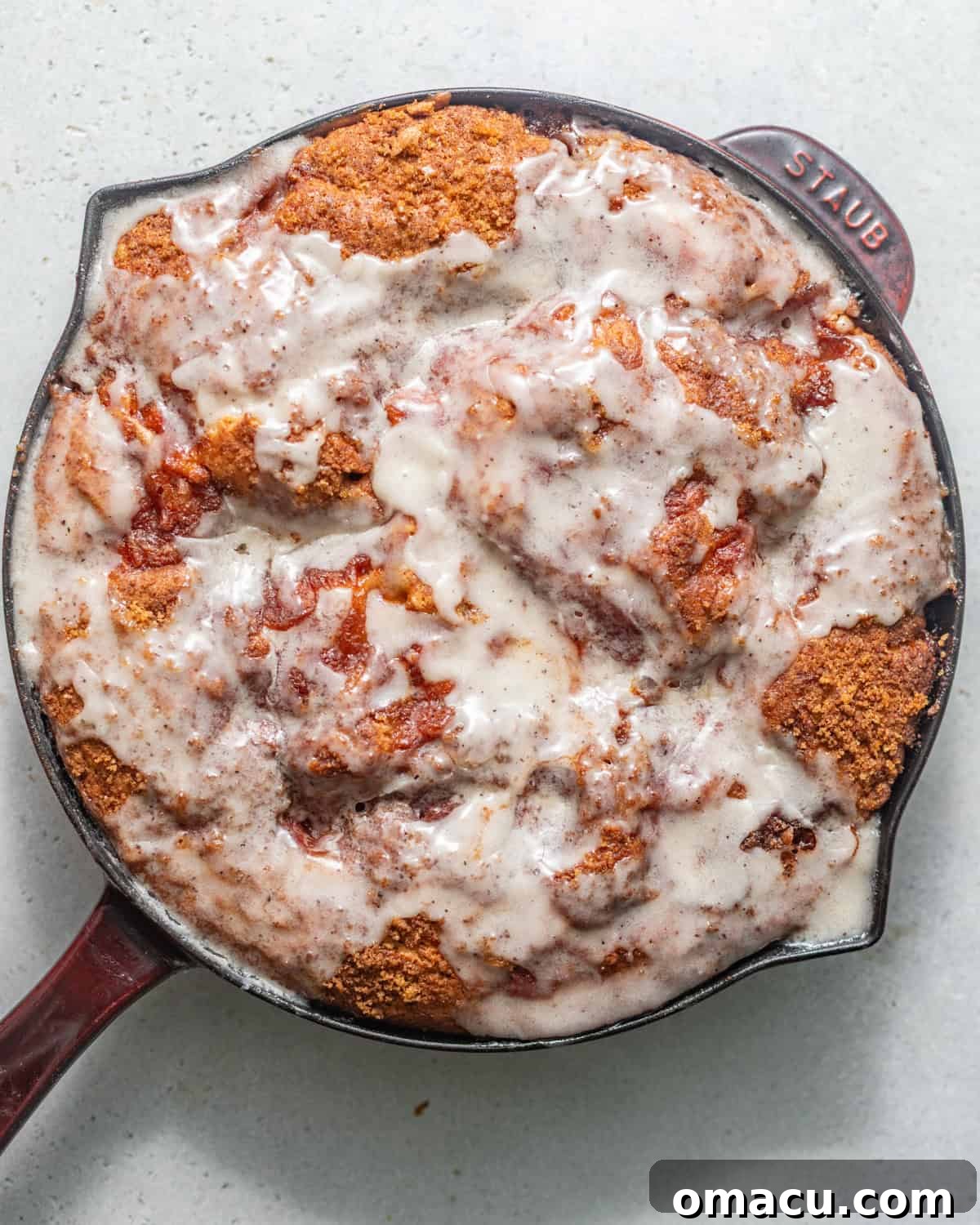 Skillet Peach Fritter Cake with Vanilla Bean Glaze 7 baked peach fritter cake in a skillet topped with vanilla bean glaze.
