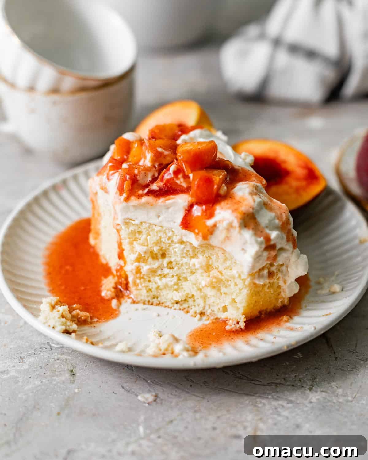 Peach Tres Leches Cobbler Recipe 9 a slice of peach tres leches on a plate with a bite taken out so that you can see the texture of the cake.