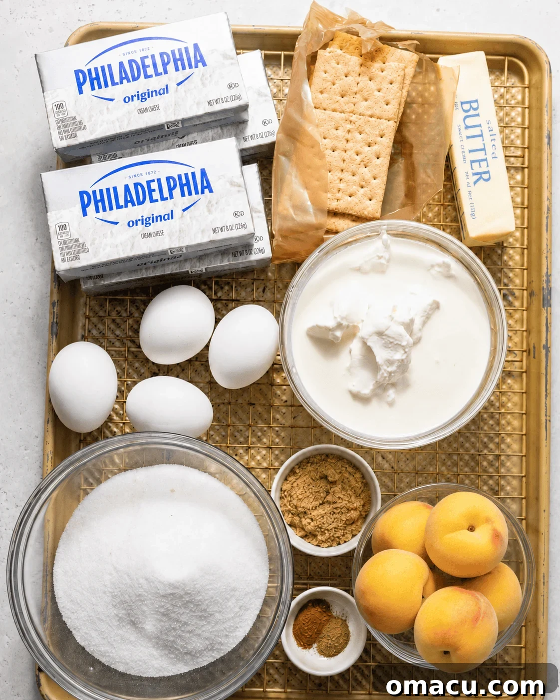 Salted Caramel Peach Cobbler Cheesecake Recipe 3 ingredients to make peach cobbler cheesecake on a baking sheet - fresh peaches, cream cheese, graham crackers, butter, heavy cream, sour cream, sug, brown sugar, eggs, and vanilla extract.