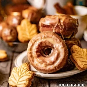 Classic Maple Cake Donuts Recipe 13 maple donuts on a plate with a small maple cookie in front of it.