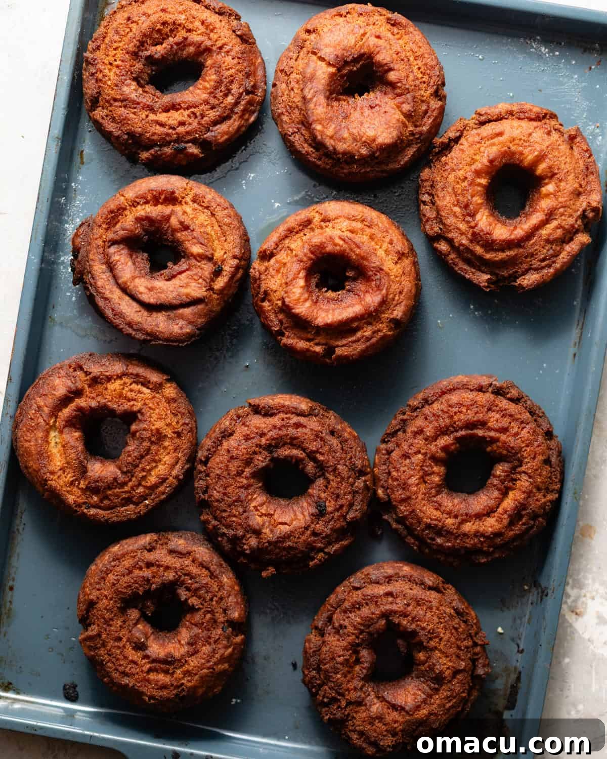 Classic Maple Cake Donuts Recipe 7 fried maple donuts on a baking sheet.