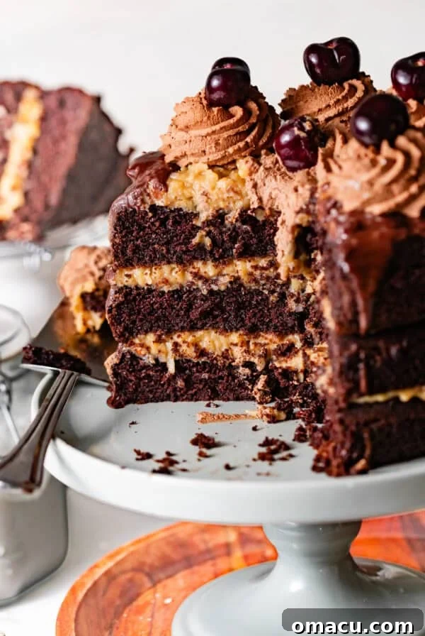 German chocolate cake with coconut pecan frosting on a cake stand with a cake server with a few slices taken out.