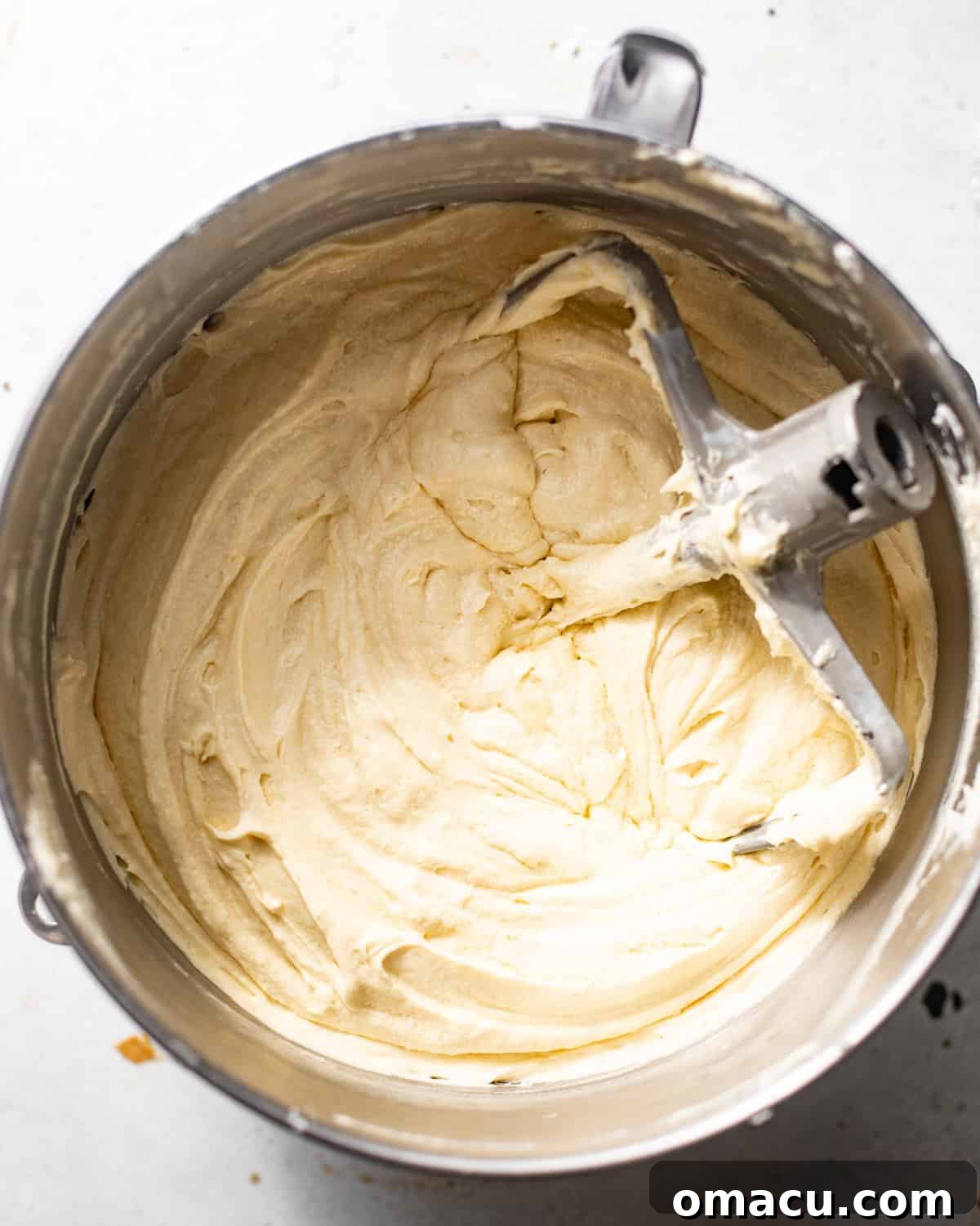 milk and honey cake batter in the bowl of a stand mixer with the paddle attachment.