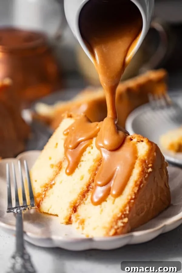 sliced caramel cake on a plate with caramel poured on top.