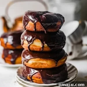 Stack of homemade chocolate glazed yeast donuts with glossy chocolate glaze dripping down the sides.