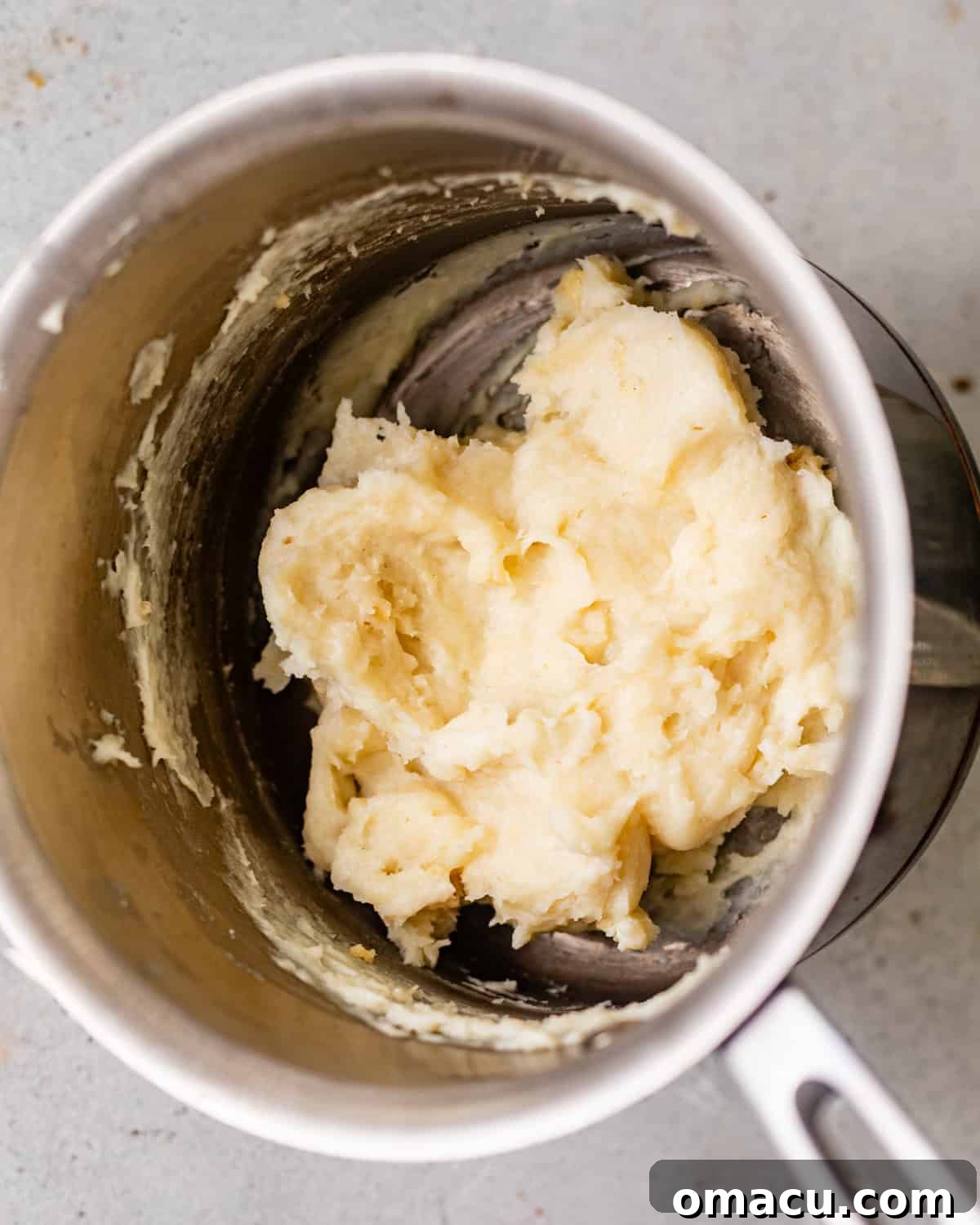Thick tangzhong paste made with milk and bread flour in a small saucepan for homemade yeast donuts.