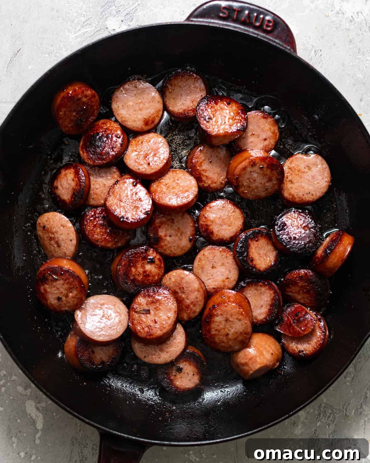 Skillet Sausage with Peppers and Onions 4 sliced sausages browned in a skillet.