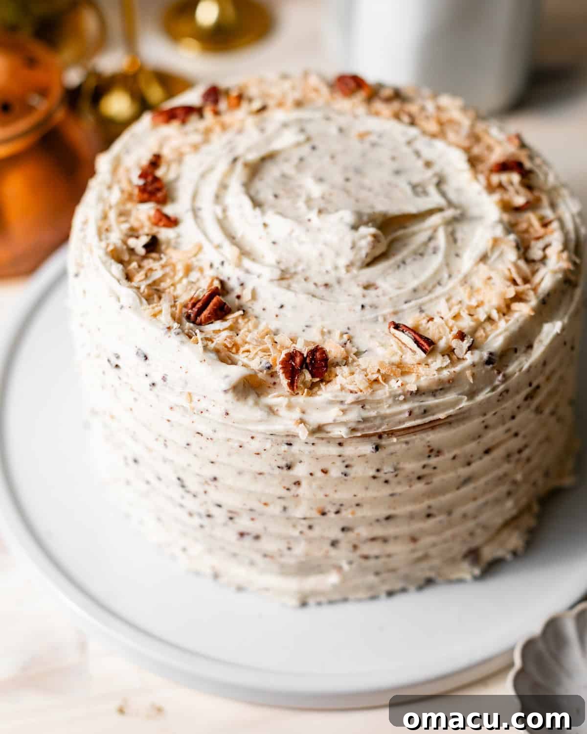 Classic Italian Cream Cake Recipe with Cream Cheese Frosting 11 Italian cream cake assembled on a cake plate and topped with toasted coconut shreds and pecans.