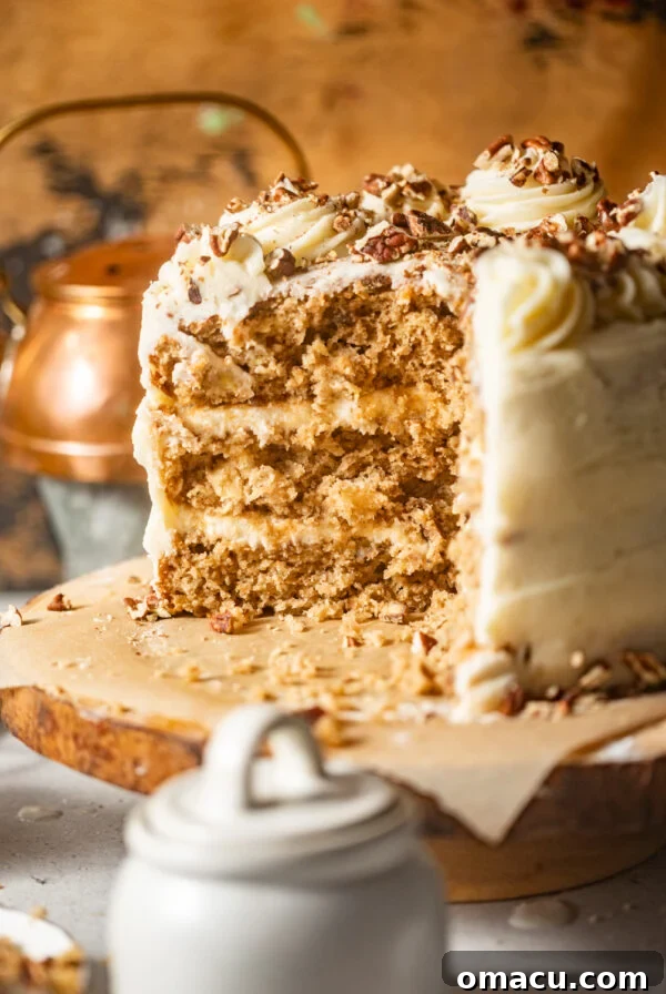 old fashioned hummingbird cake on a cake stand with a piece cut out of it so you can see the inside of the cake.