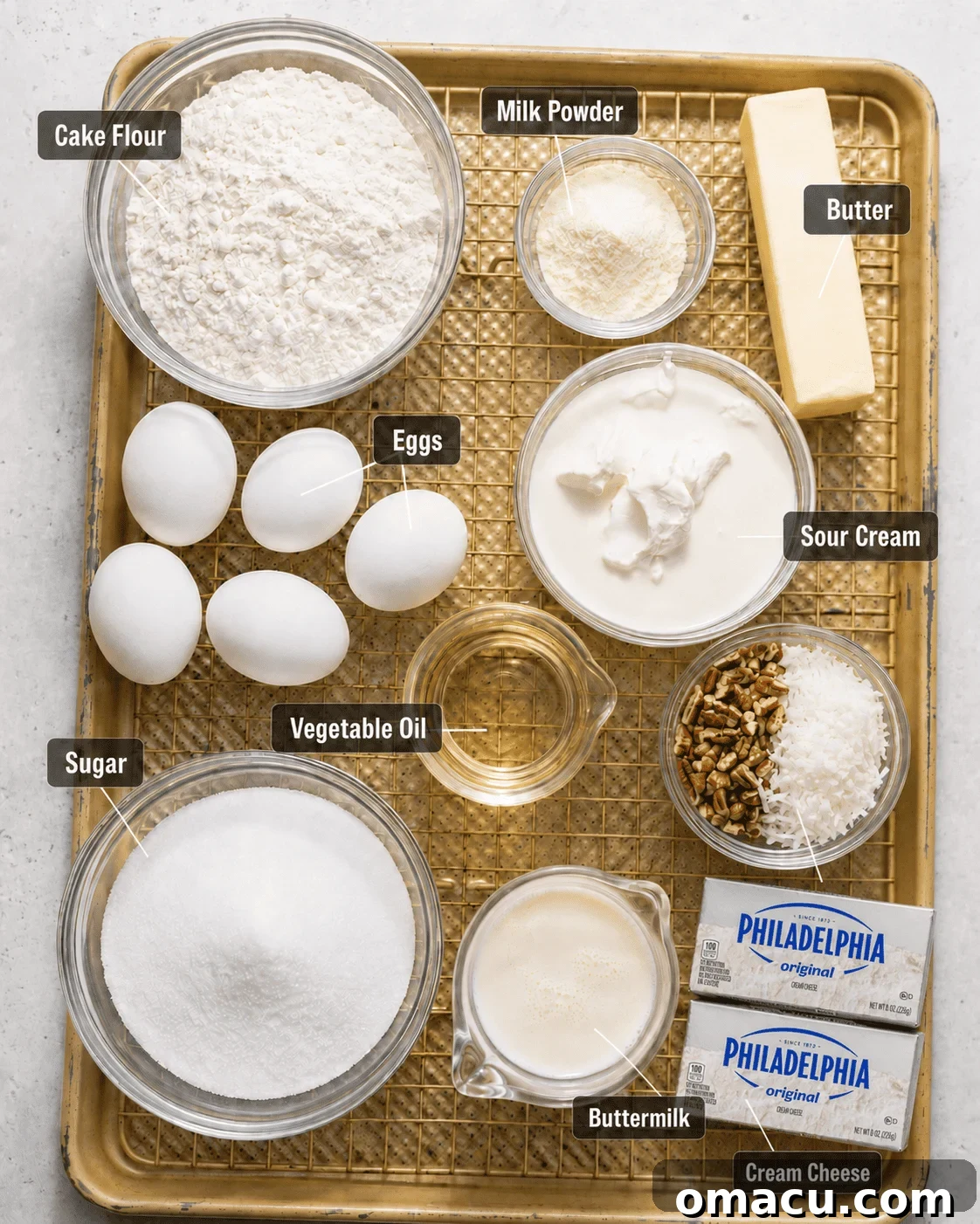 Classic Italian Cream Cake Recipe with Cream Cheese Frosting 3 Italian cream cake main ingredients on a baking sheet in a small bowl including cake flour, sugar, milk powder, eggs, buttermilk, sour cream, pecans, coconut, vegetable oil, butter, and cream cheese.
