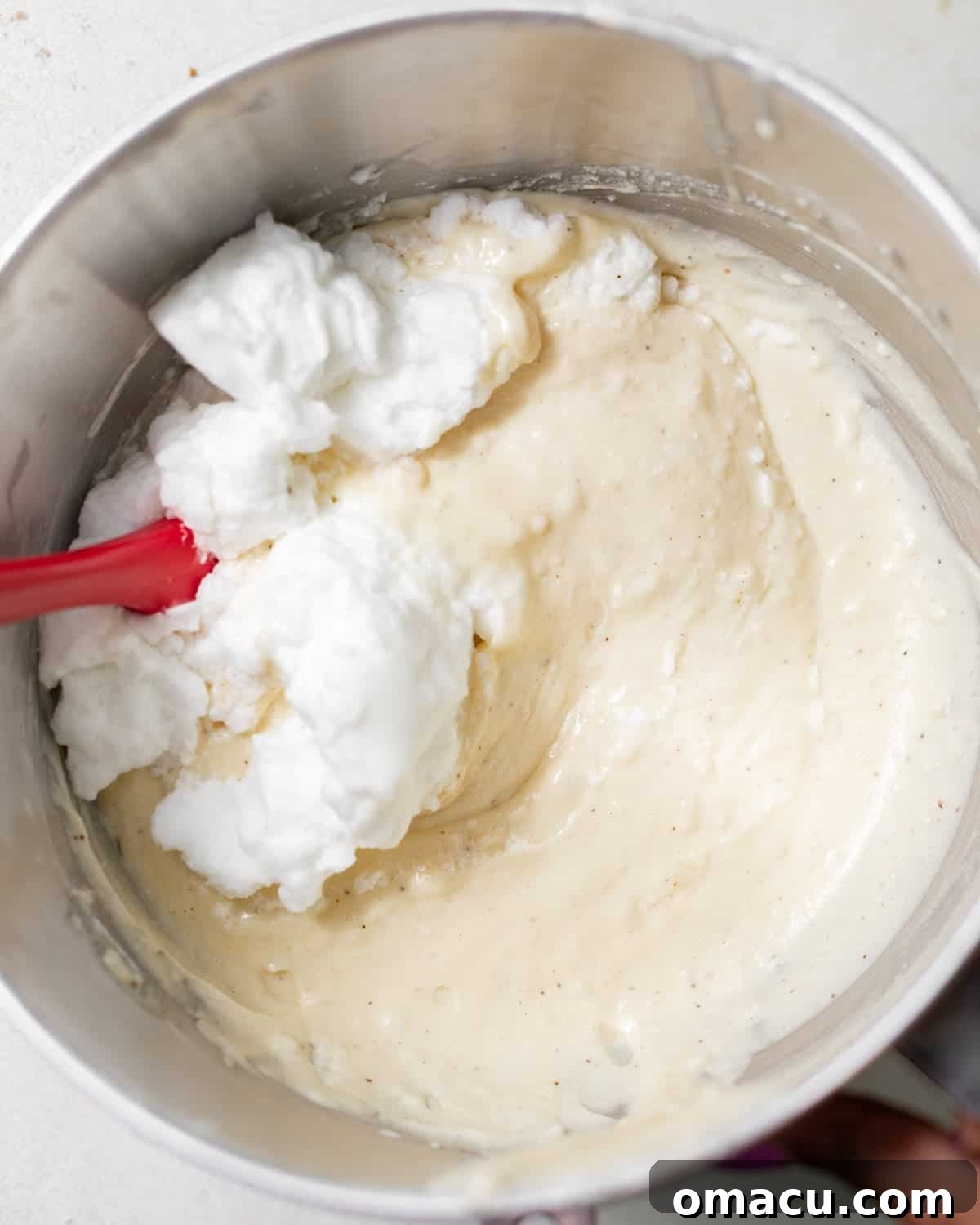 Classic Italian Cream Cake Recipe with Cream Cheese Frosting 8 Whipped egg whites being folded gently into Italian cream cake batter.