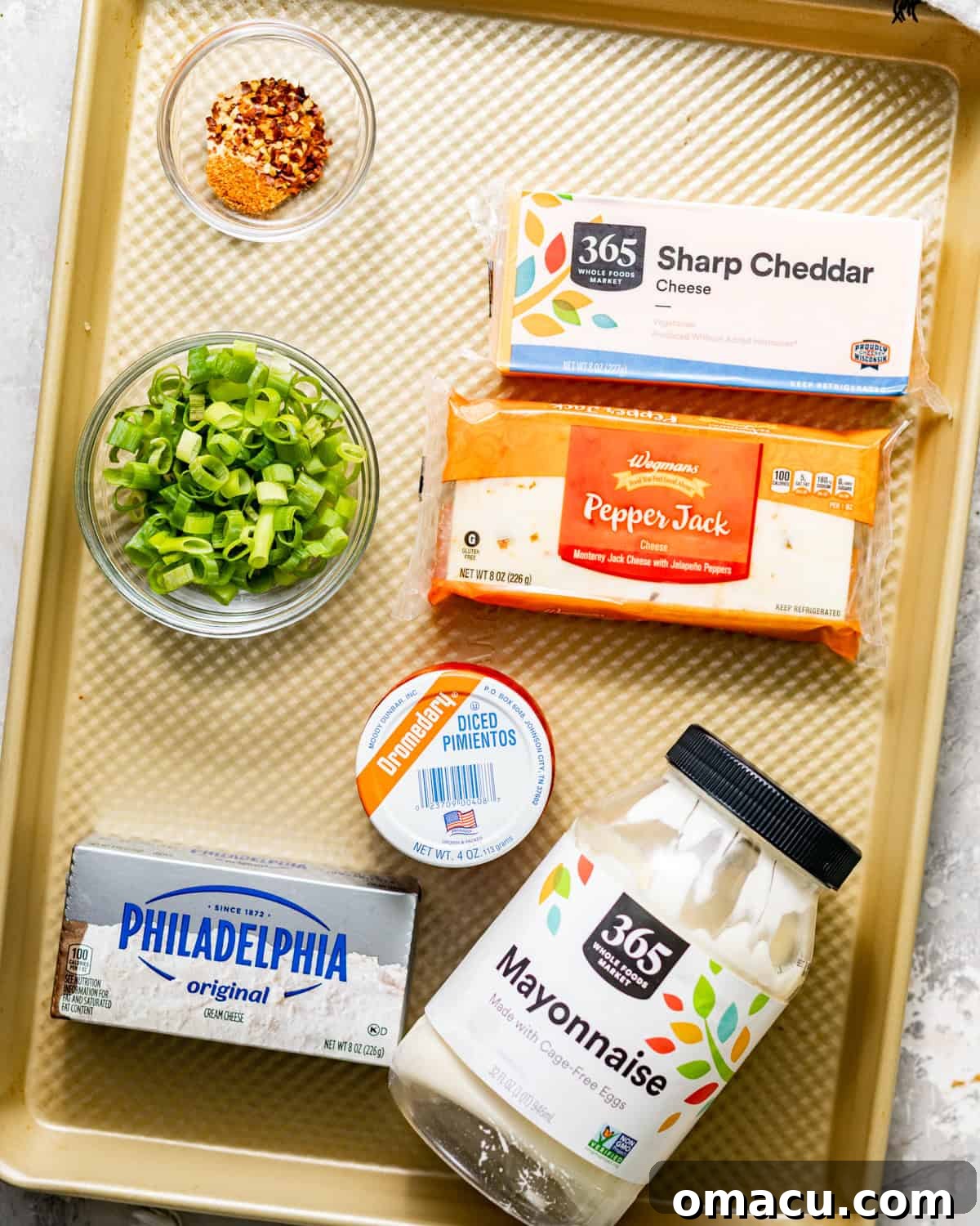 Creamy Southern Pimento Cheese Dip for Game Day 3 ingredients to make pimento cheese on a baking sheet - cheddar cheese, mayo, pepper jack cheese, scallions, diced pimentos, seasonings, and hot sauce.