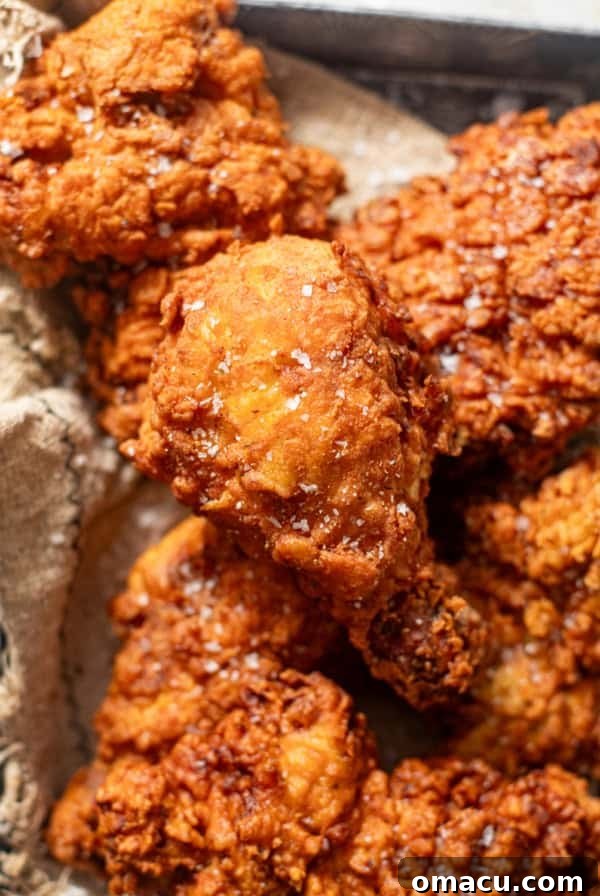 piece of fried chicken in a serving basket with a sprinkle of flaky sea salt on top.
