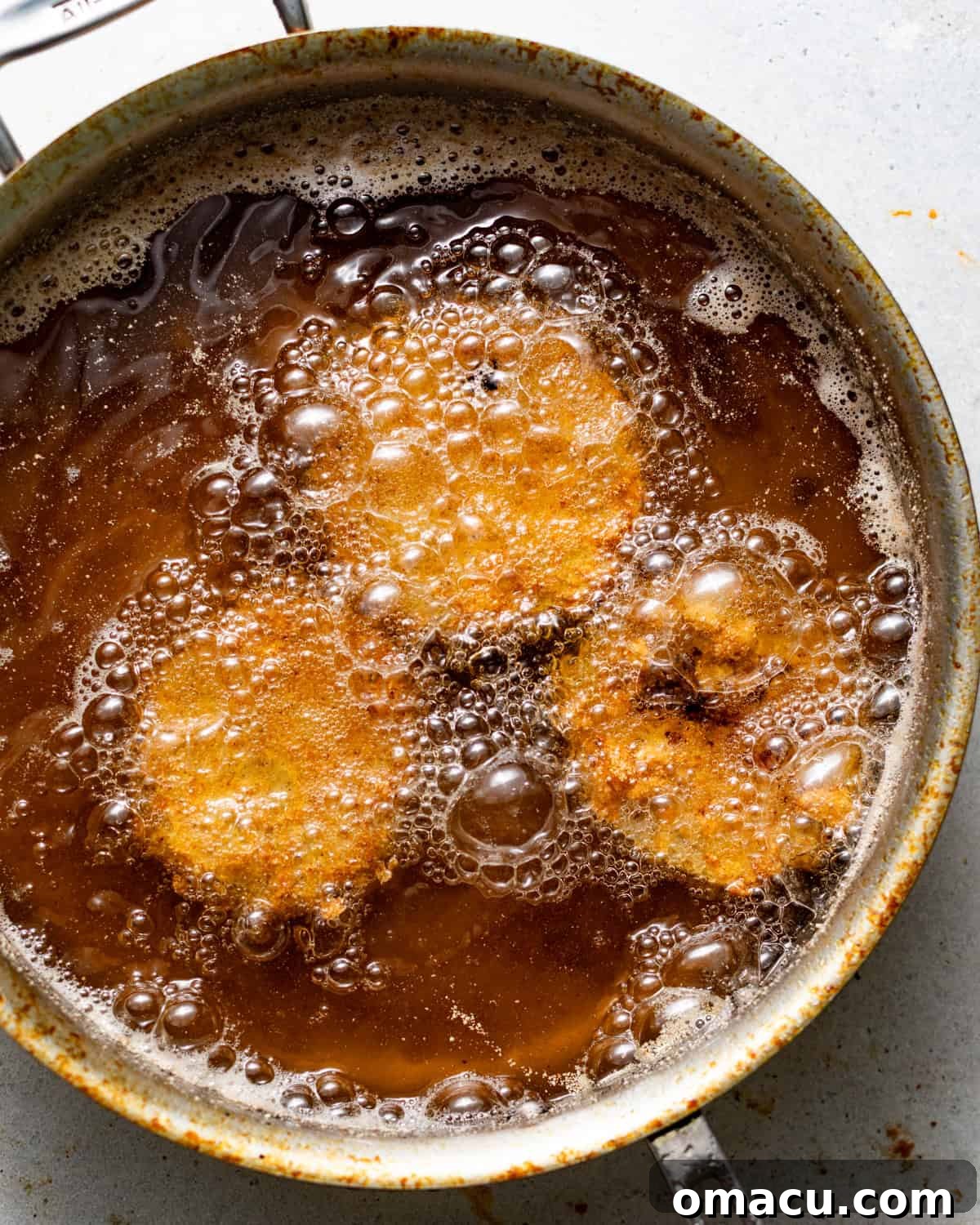Crispy Southern Fried Green Tomatoes Recipe 7 breaded green tomato slices frying in a skillet.