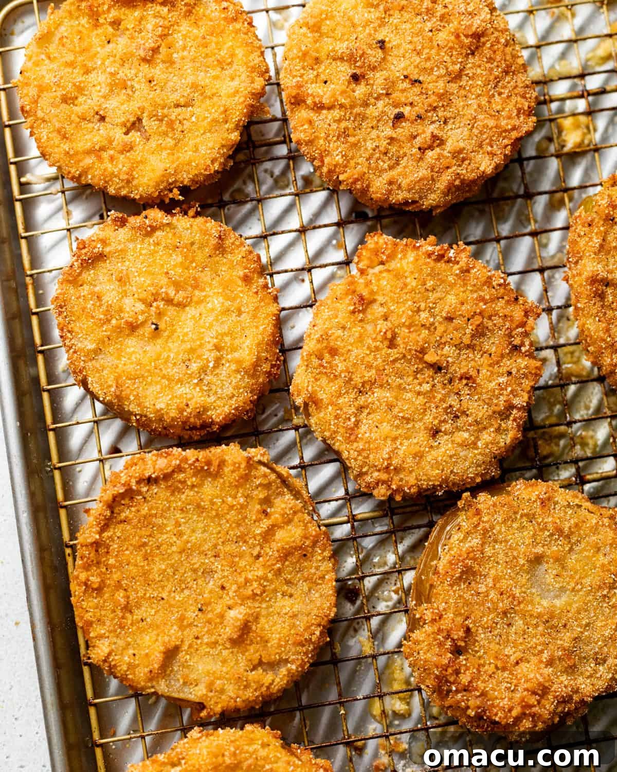 Crispy Southern Fried Green Tomatoes Recipe 8 fried green tomatoes resting on a wire rack after frying.
