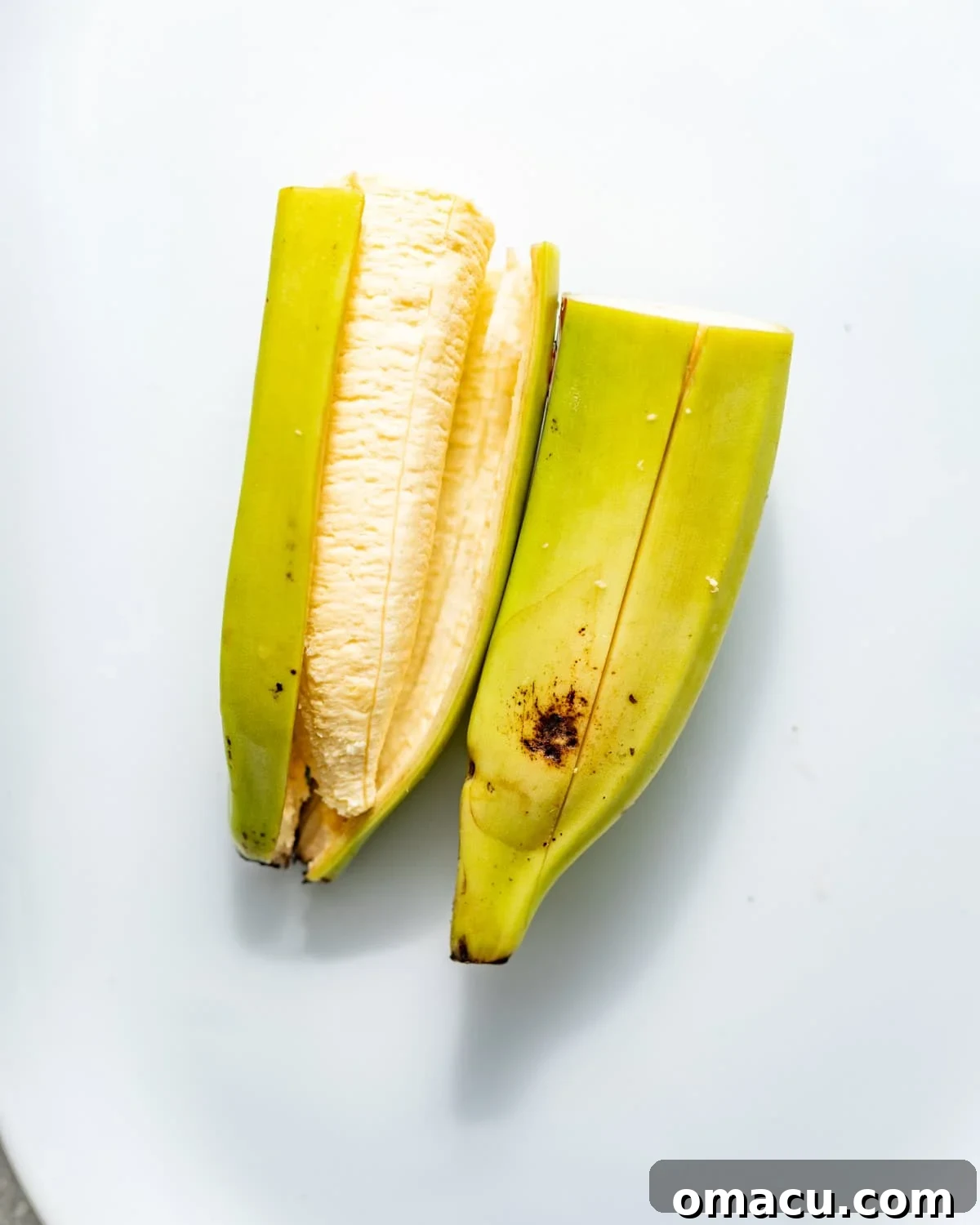 Crispy Tostones Recipe: Authentic Fried Plantains 4 a plantain cut in half with a slit down the middle to make removing the skin easier.