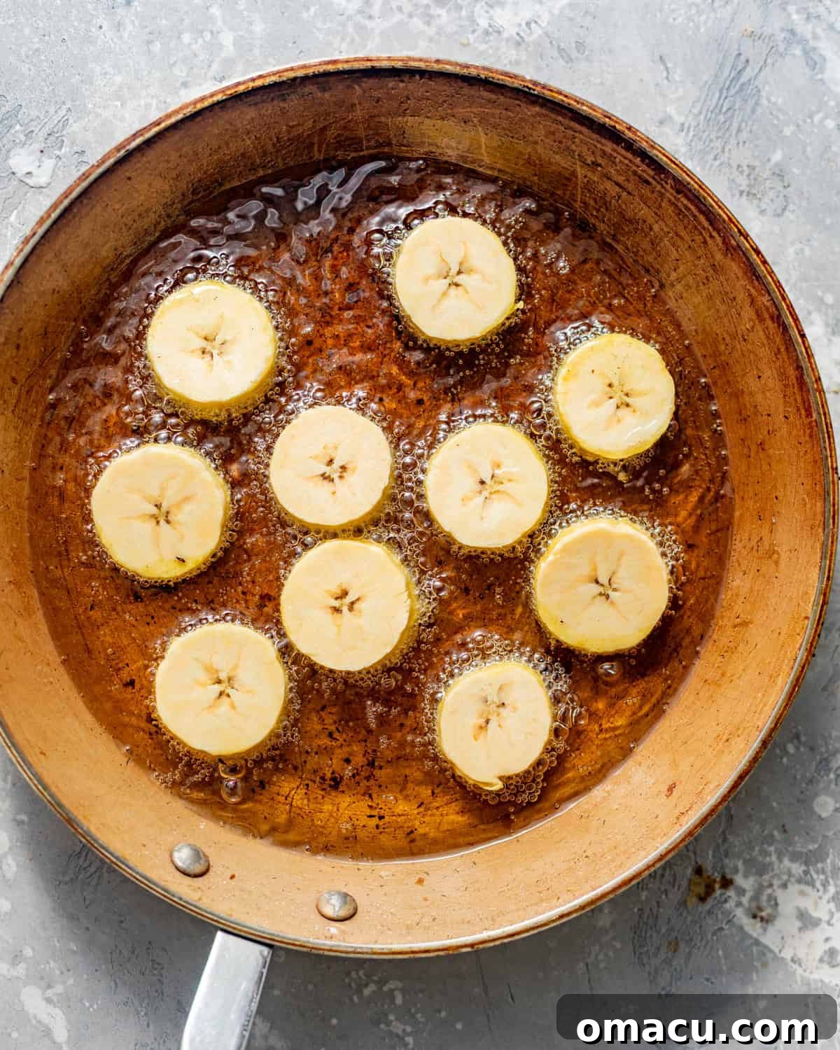 Crispy Tostones Recipe: Authentic Fried Plantains 6 sliced plantains frying in a skillet.