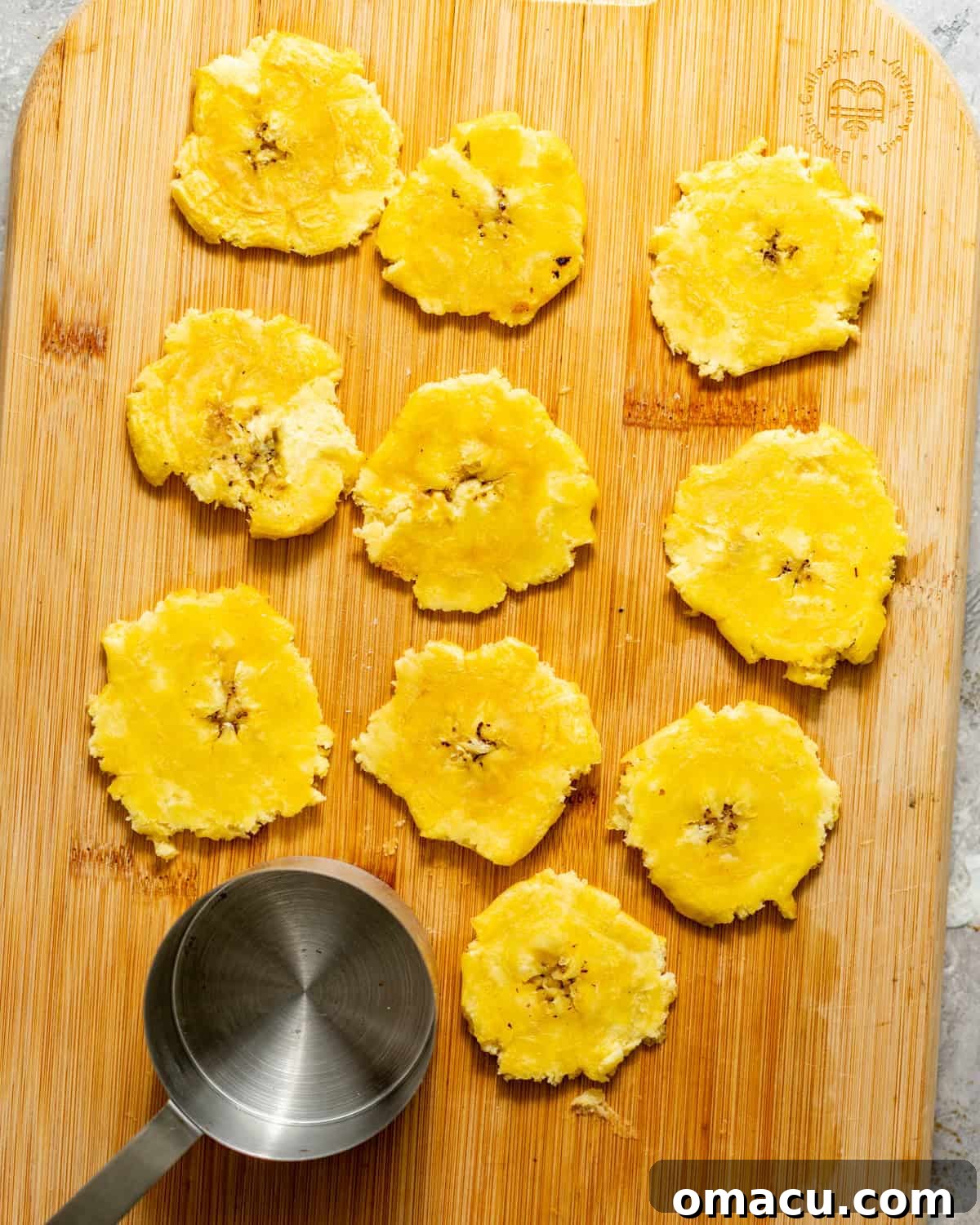 Crispy Tostones Recipe: Authentic Fried Plantains 7 smashed plantains on a cutting board.