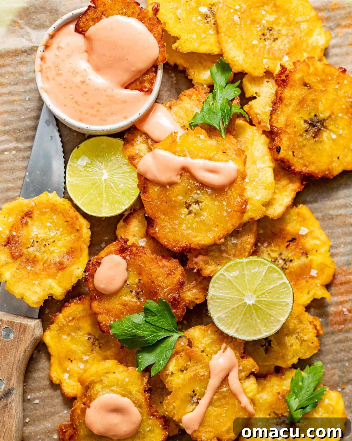 Crispy Tostones Recipe: Authentic Fried Plantains 9 fried tostones on a plate with mayo ketchup in a small bowl.