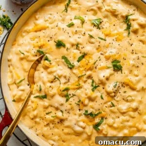 stovetop mac and cheese in a pot with a wooden spoon and garnished with parsley.