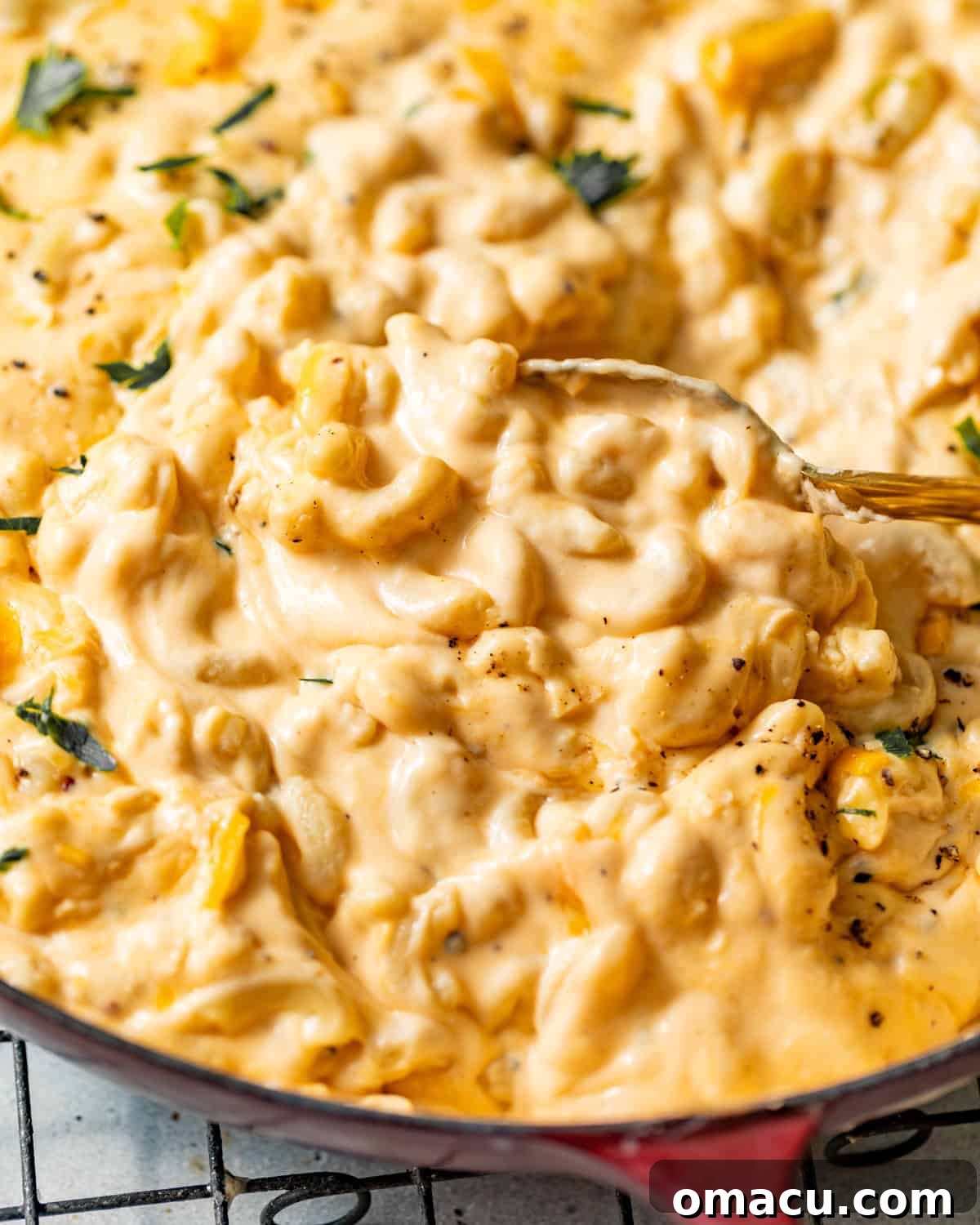 Spoonful of creamy stovetop mac and cheese lifted from a red skillet, showing the thick, velvety cheese sauce.