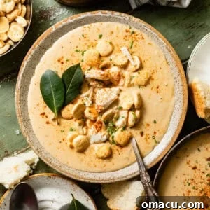 Classic She-Crab Soup: Southern Creamy Crab Recipe 12 she crab soup in a bowl with a spoon topped with oyster crackers, jumbo lump crab, and a dash of old bay seasoning.